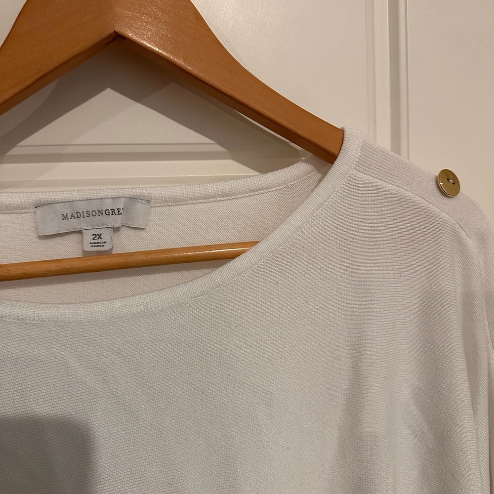 White sweater top with gold accent buttons.